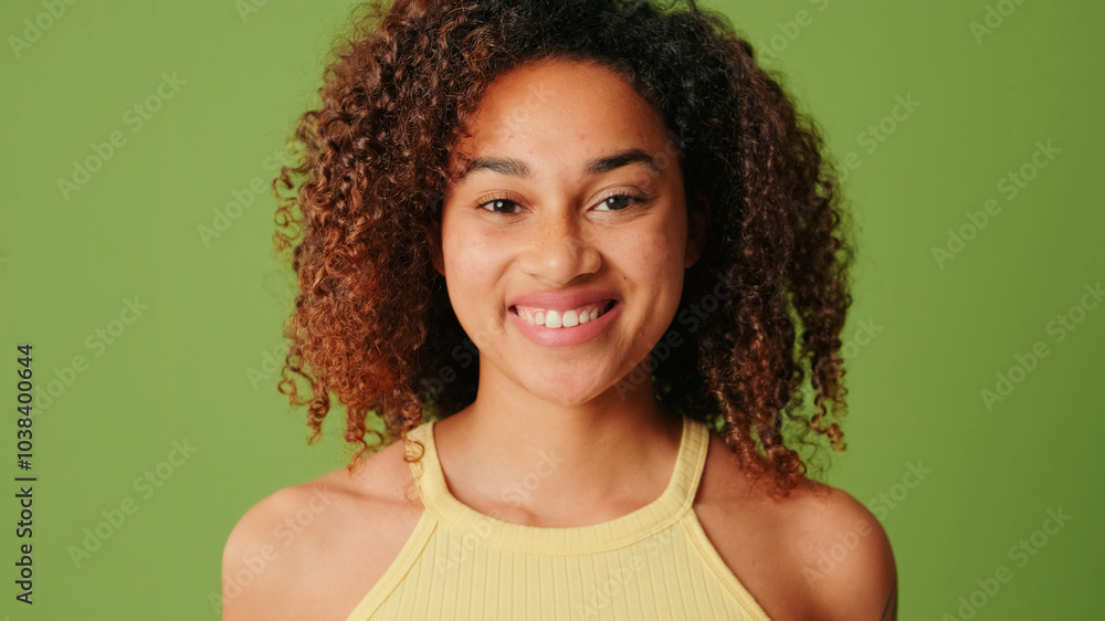 The positive woman smiles shyly to camera on green screen background, Close-up The positive woman smiles shyly to camera on green screen background, Close-up