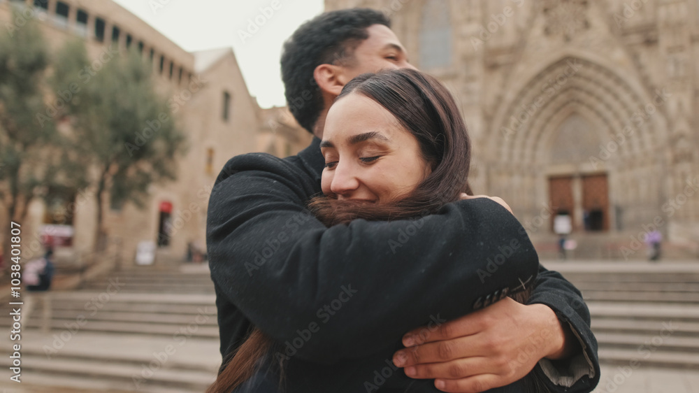 Romantic young couple embracing in front of historic cathedral, sharing moment on cloudy day Romantic young couple embracing in front of historic cathedral, sharing moment on cloudy day