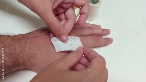 Putting gauze and plaster over an abrasion wound on the hand to prevent infection and promote healing 