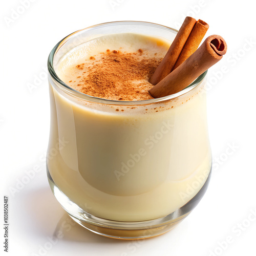 Low-angle close-up of a glass of eggnog with cinnamon dusting on top, isolated on a white background