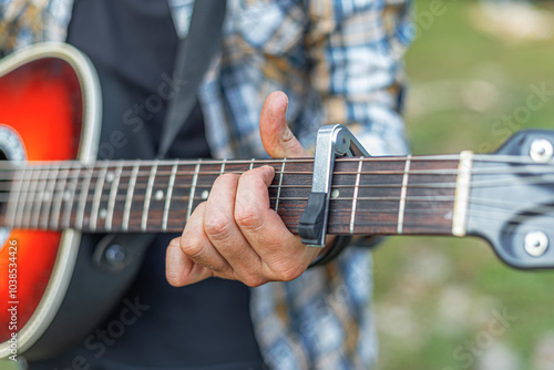 Obraz na płótnie Male hands with an acoustic guitar against a background of a country landscape. w salonie