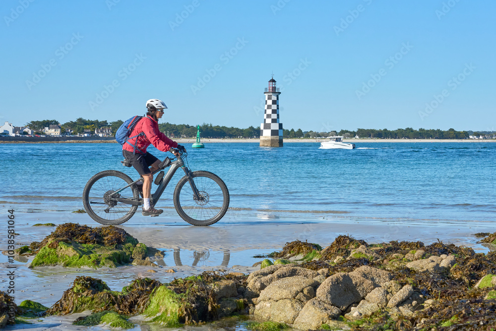 Φωτογραφία active senior woman cycling with her electric mountain bike along the beach of L