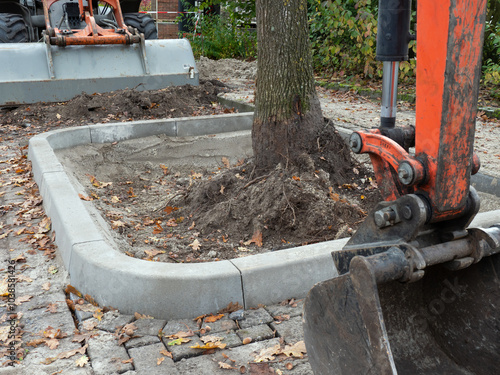 Entsiegelung Baumscheibe - Baumaschinen und vergrößerte Baumgrube mit Einfassung am Straßenrand photo