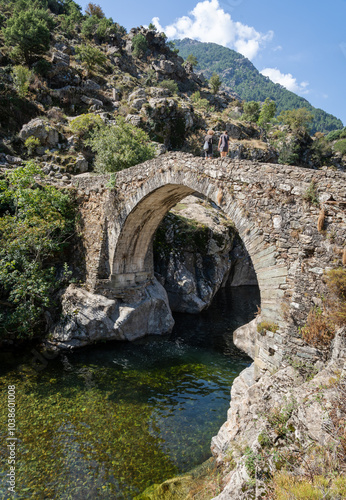 Two people standing on the historic Genoese bridge in Asco, Corsica, France photo