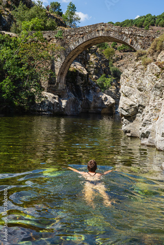 Female is bathing in a river at the historic Genoese bridge in Asco, Corsica photo