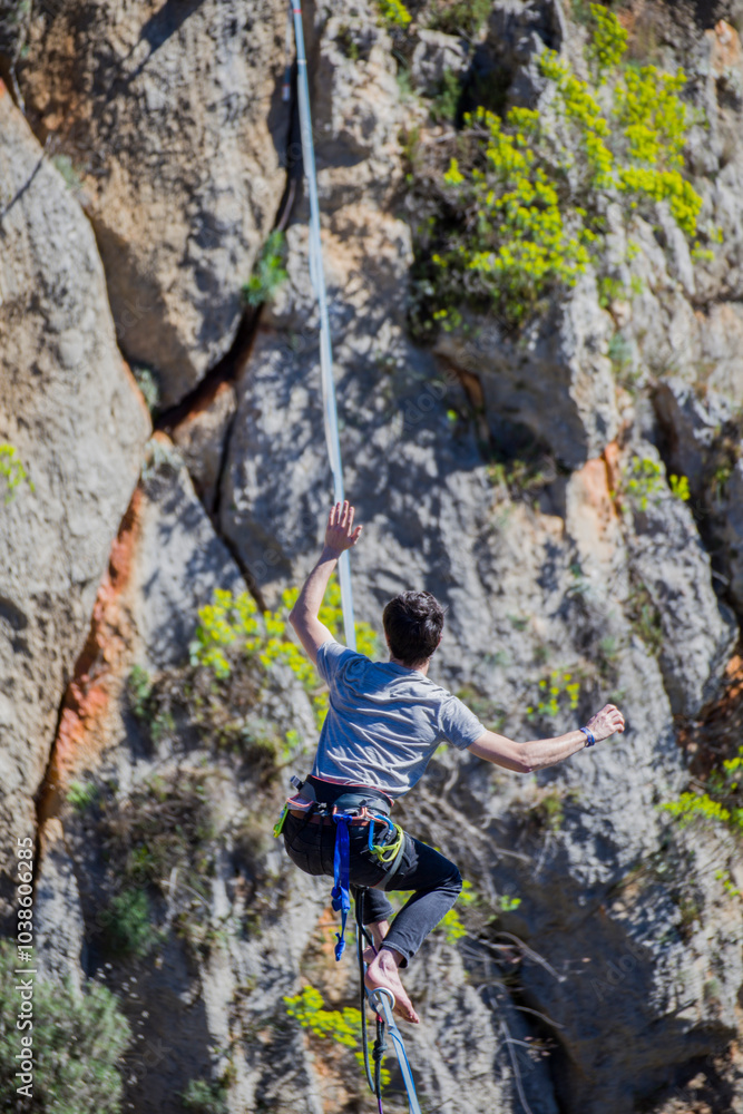 A tightrope walker walks along a cable stretched over a canyon. A tightrope walker walks along a cable stretched over a canyon.