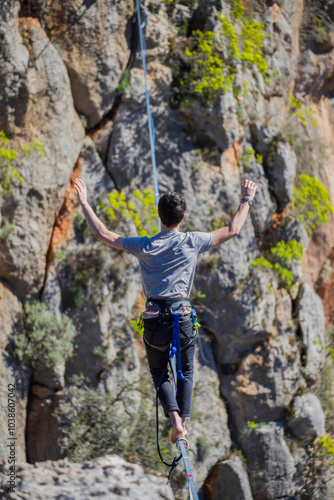 A tightrope walker walks along a cable stretched over a canyon.