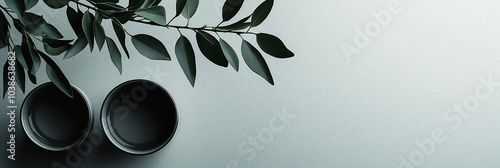 A minimalist composition of two tea cups and leaves on a simple backdrop, evoking a sense of calm and balance. photo