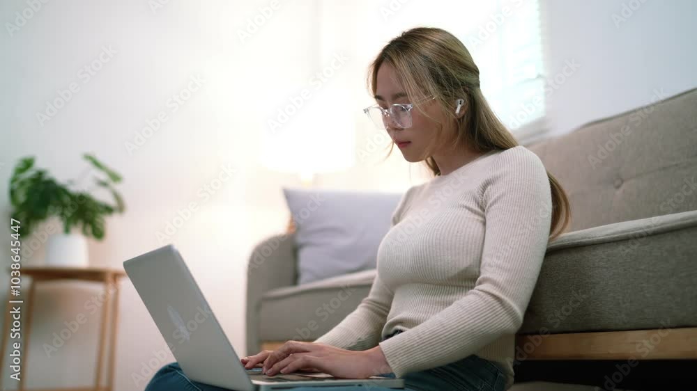 A young woman sits on the floor with a laptop on her lap, looking relaxed. She is wearing a sweater, and the room has soft lighting and a plant in the background A young woman sits on the floor with a laptop on her lap, looking relaxed. She is wearing a sweater, and the room has soft lighting and a plant in the background