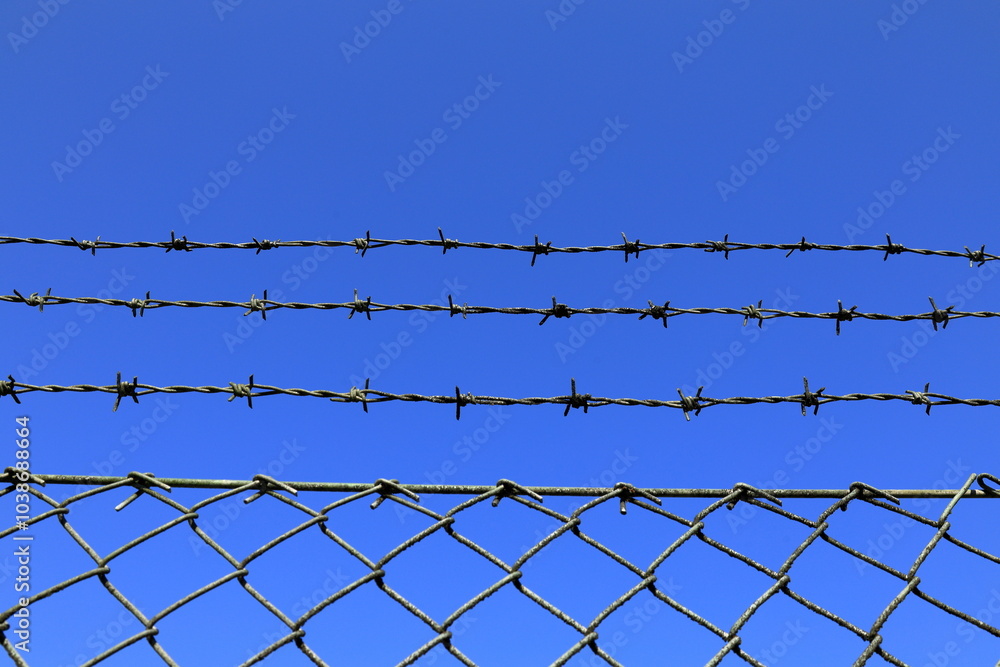 Barb wire fence. Blue sky as background. Barb wire fence. Blue sky as background.