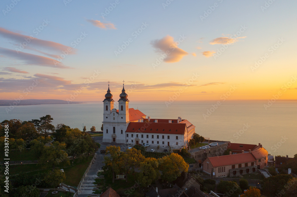 Fototapeta premium Tihany, Hungary - Aerial skyline view about the famous Benedictine Monastery of Tihany (Tihany Abbey) with beautiful colourful sky and clouds at sunrise.