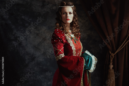 medieval queen in red dress on dark gray background