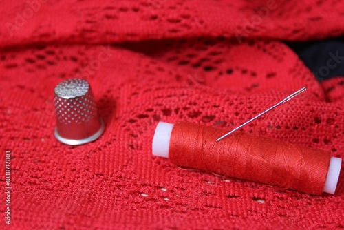 Red sewing thread and needle on lace fabric. photo