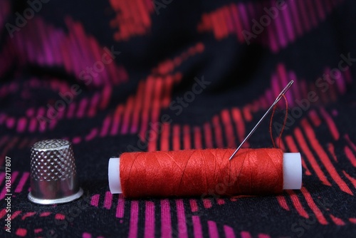 Red thread spool with needle and thimble. photo