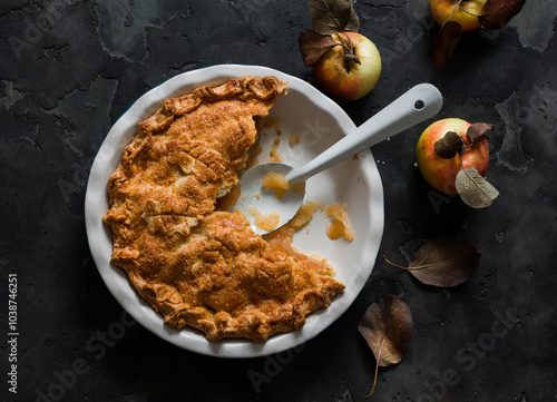 Traditional Irish apple pie in a baking dish, apples on a dark background, top view