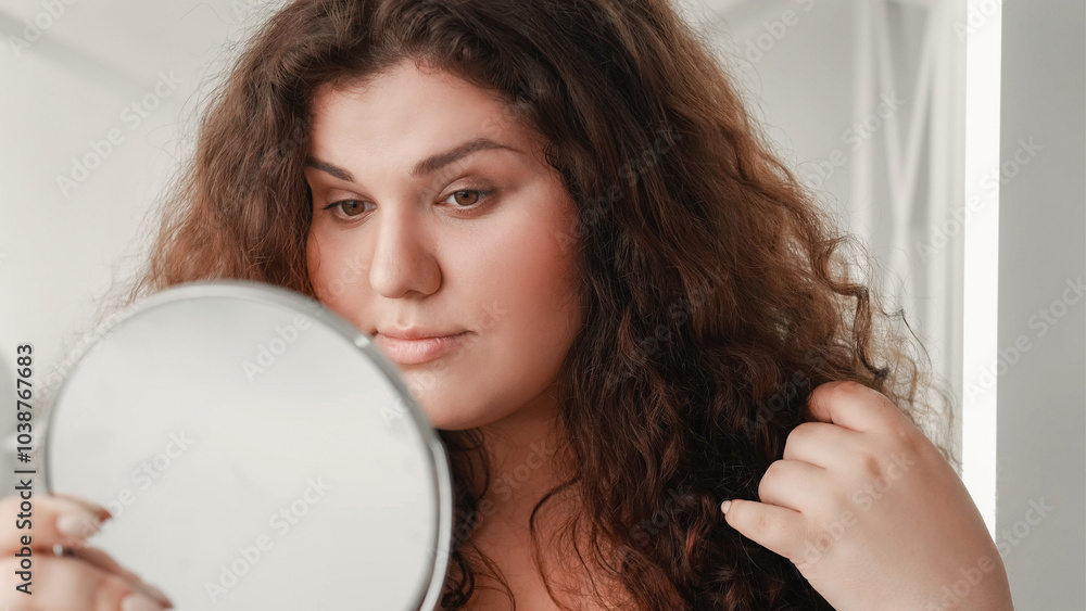 Morning skincare. Natural beauty. Health wellness. Confident overweight woman with clean face skin looking in mirror on light free space. Morning skincare. Natural beauty. Health wellness. Confident overweight woman with clean face skin looking in mirror on light free space.