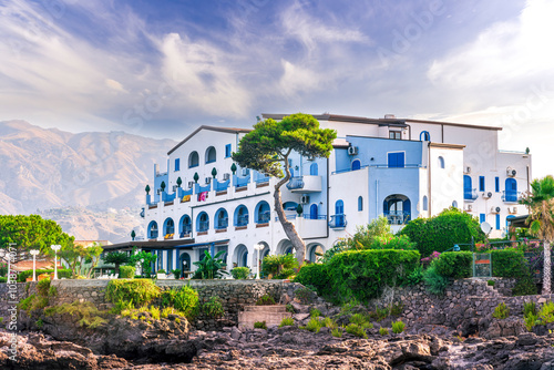 summer beautiful view of nice hotel resort building in greek style on sea coast with amazing mountains and clouds on background of landscape photo