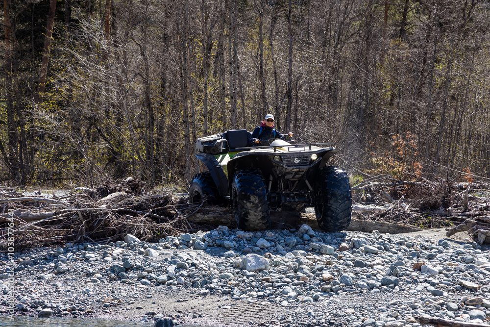 Girl on a quad bike in the mountains. Mountain river. Beautiful landscape. Large all-terrain vehicle. Girl on a quad bike in the mountains. Mountain river. Beautiful landscape. Large all-terrain vehicle.