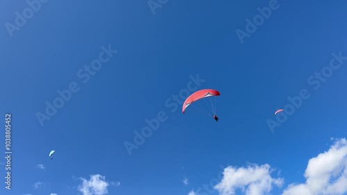 Soaring on a paraglider over the mountains against a clear blue sky. Extreme sports