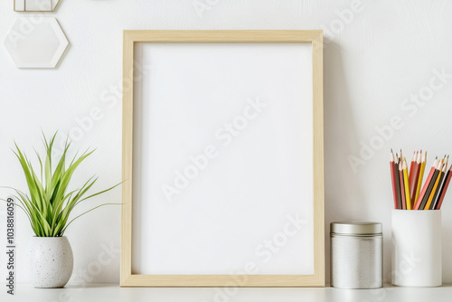 minimalist workspace featuring blank wooden frame, potted plant, metal canister, and colorful pencils in white holder. This serene setup invites creativity and organization