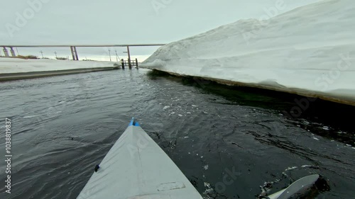 kayaker swims along the ice wall slowing down with a paddle