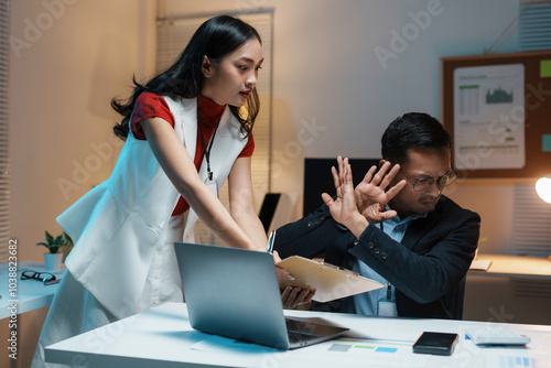 Fotografia Businesswoman holding a report is standing next to her seated male colleague who