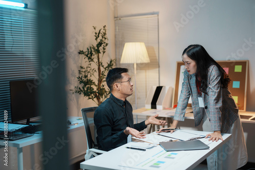 Two business colleagues having a disagreement while working together at a desk in an office at night