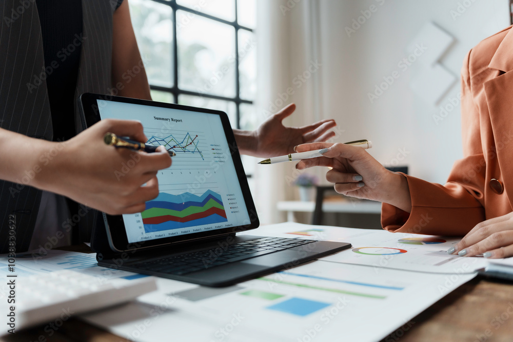 Business partners reviewing financial data on a tablet, analyzing graphs and discussing business strategy Business partners reviewing financial data on a tablet, analyzing graphs and discussing business strategy