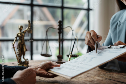 Lawyer is pointing with a pen on important details of a contract while explaining it to a client in law firm office