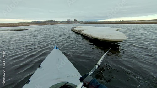 A kayak navigates through icy waters in the Arctic, showcasing the serene beauty and harsh conditions of this remote environment. Ideal for adventure, travel, and nature documentaries.