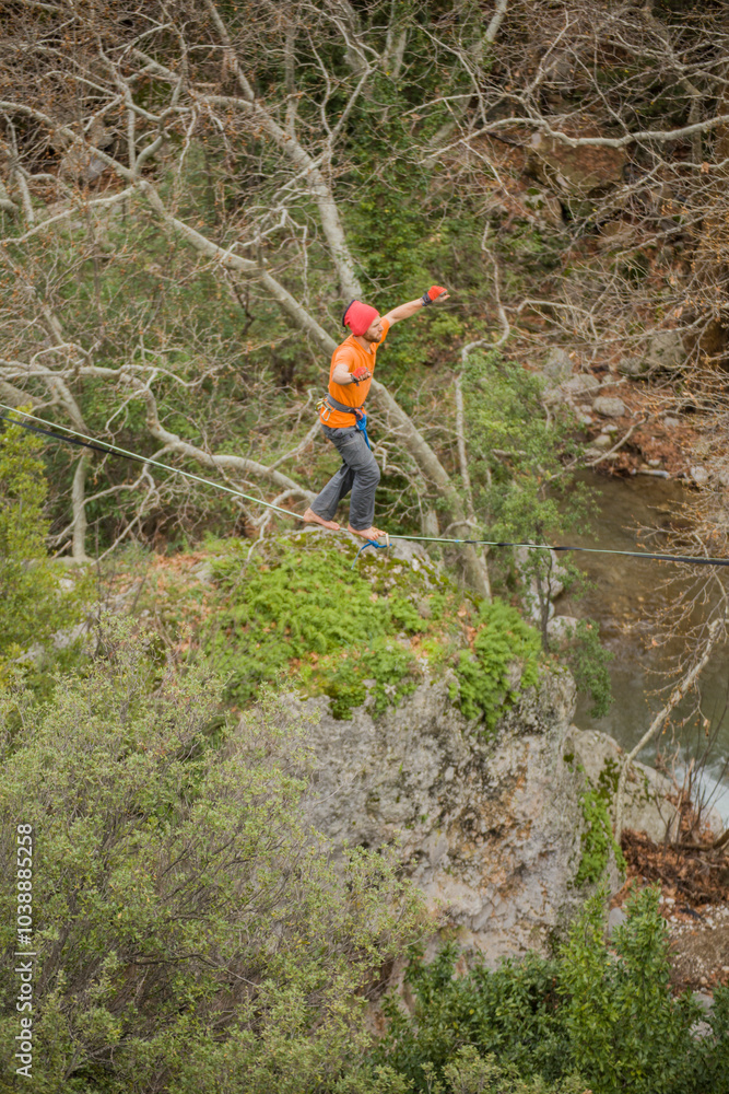 A tightrope walker walks along a cable stretched over a canyon. A tightrope walker walks along a cable stretched over a canyon.