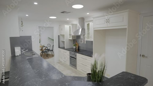 Magnificent white furnished kitchen with silver-golden details, marble countertop, and oven.