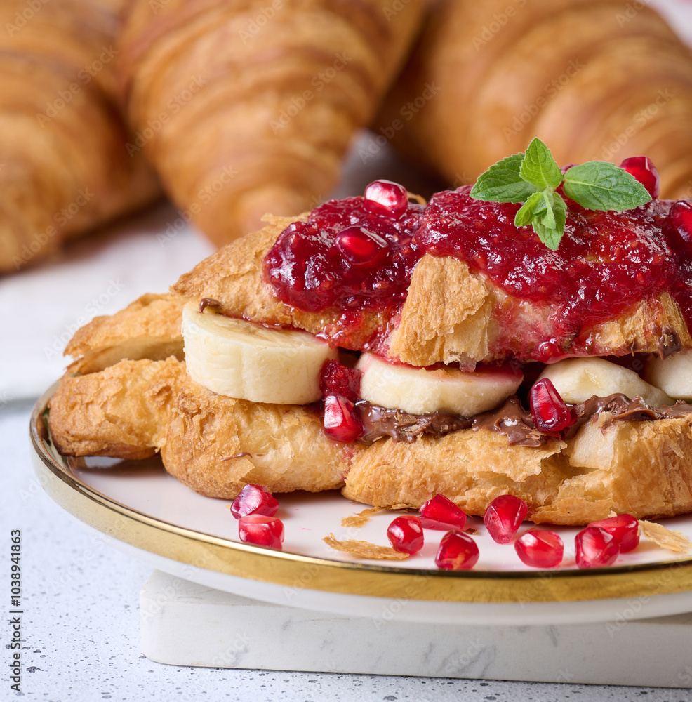 Croissant with chocolate, banana pieces and raspberry jam on a plate Croissant with chocolate, banana pieces and raspberry jam on a plate