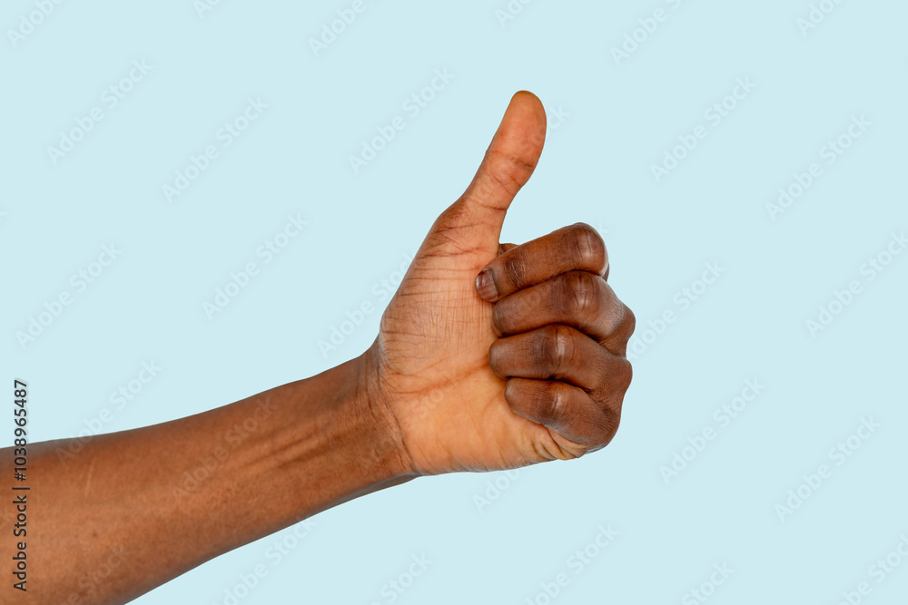 A joyful hand gesture expressing approval against a light blue backdrop at midday A joyful hand gesture expressing approval against a light blue backdrop at midday