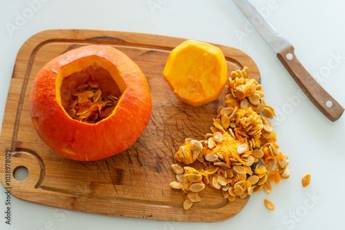 Halloween pumpkin gutting before carving Jack-o'-lantern. Guts and seeds inside a pumpkin being removed with knife, through cut off top lid.