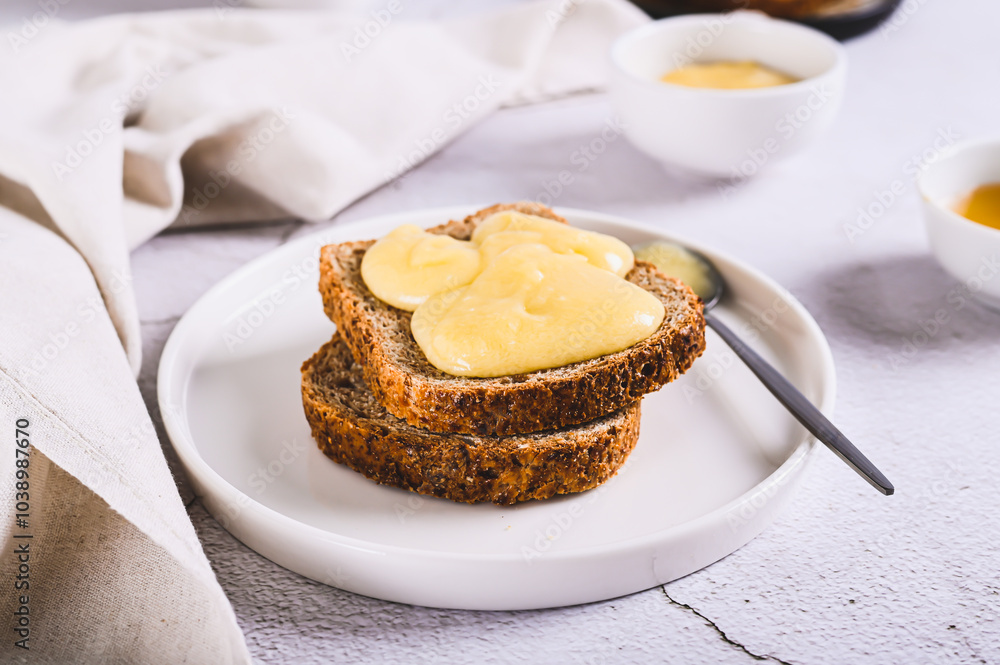 Morning sandwiches on grain bread with honey butter on a plate on the table