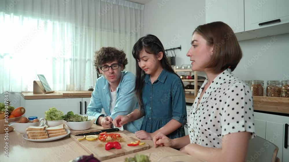 Attractive caucasian father and mother spend time together to cook fresh meal with asian daughter. Dad and mom preparing fresh vegetable for making salad at kitchen and eating vegetable. Pedagogy. Attractive caucasian father and mother spend time together to cook fresh meal with asian daughter. Dad and mom preparing fresh vegetable for making salad at kitchen and eating vegetable. Pedagogy.