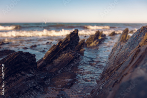 Beautiful sharp stones on the seashore, washed by the waves. Stone ridges on a wild beach. Smooth and long stone formations going into the sea. Beautiful photo of marine nature photo