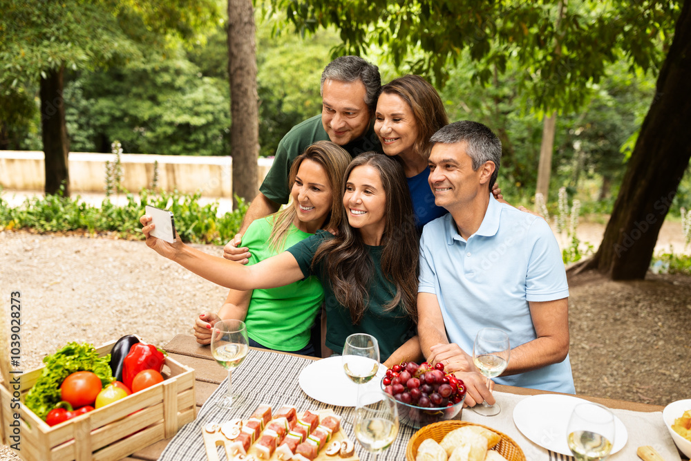 A group of five friends gathers around a table loaded with fresh fruits and snacks, smiling as they take a selfie in a vibrant garden during a summer day. A group of five friends gathers around a table loaded with fresh fruits and snacks, smiling as they take a selfie in a vibrant garden during a summer day.