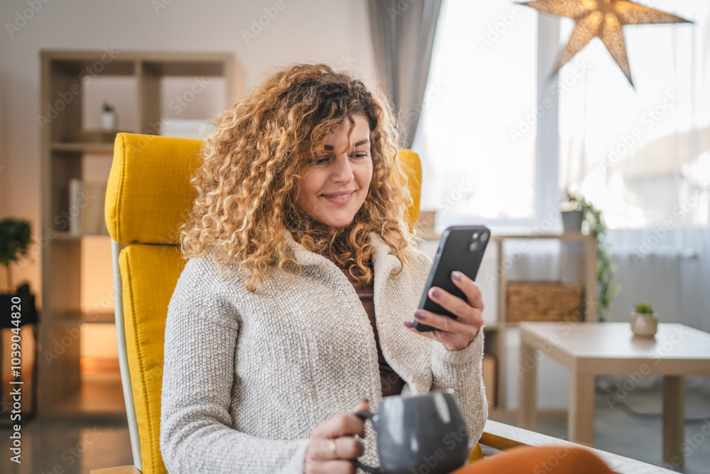 © Miljan Živković - One woman with curly hair at home use mobile phone smartphone sms texting or browse internet
