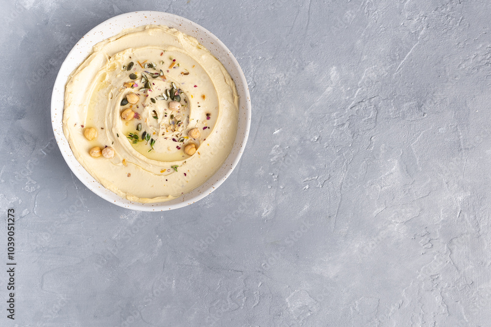 Hummus with olive oil in a gray ceramic plate. Toast and breadsticks for snacks. Top view, on a gray background. Hummus with olive oil in a gray ceramic plate. Toast and breadsticks for snacks. Top view, on a gray background.