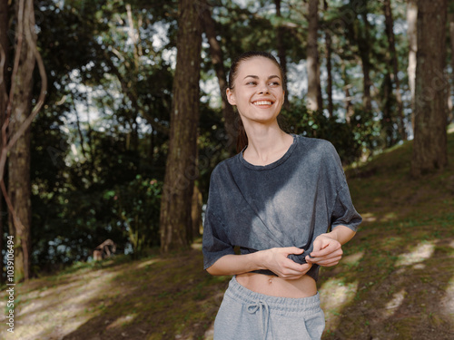 Smiling young woman in casual outfit standing in a green forest, enjoying nature and serene surroundings Personal growth and outdoor lifestyle concept