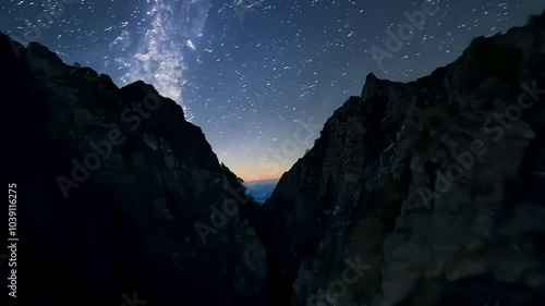 Starry night sky over dark rocky landscape photo