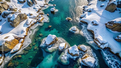 An aerial view of a river winding through a snow-covered landscape, revealing a turquoise expanse of water and scattered islands of rock dusted with fresh powder. photo