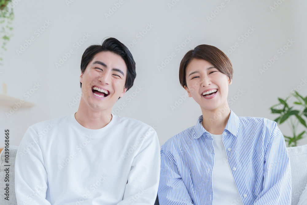 家のリビングで過ごす笑顔の30代夫婦 家のリビングで過ごす笑顔の30代夫婦
