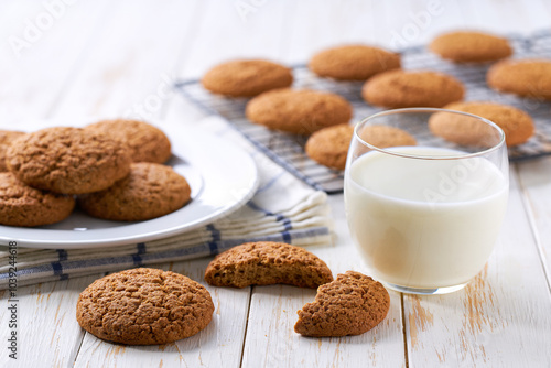 Tasty oatmeal cookies and glass milk on a light kitchen table, selective focus.