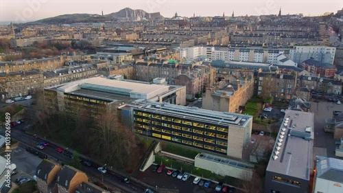 Wallpaper Mural Drone footage capturing a blend of modern office buildings and traditional Edinburgh residential architecture. Arthur’s Seat is visible in the background, showcasing the city’s iconic skyline. Torontodigital.ca
