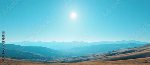 A panoramic view of a mountain range under a bright blue sky with a sun shining brightly in the center of the image.