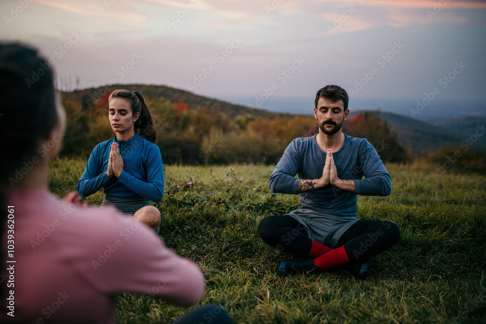 Fit sporty people practicing yoga and meditating during a late sunset period of a day outdoors Fit sporty people practicing yoga and meditating during a late sunset period of a day outdoors
