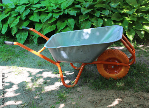 Empty garden wheelbarrow at the backyard of a summer cottage. Garden care and farming illustration stock photo